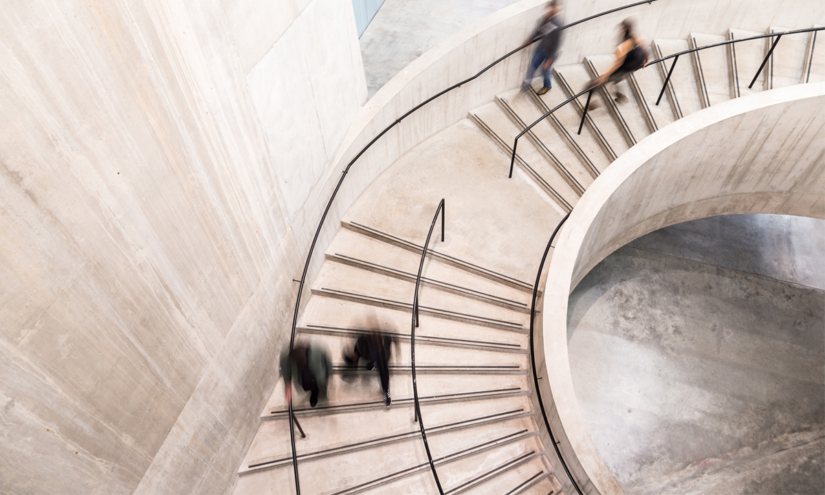 Blurry picture of people on a large concrete spiral staircase
