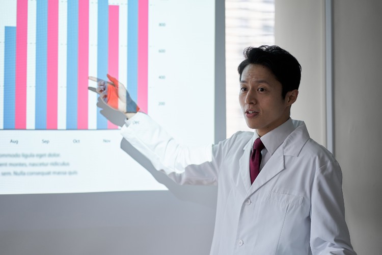 Male doctor pointing at a bar chart in a Powerpoint presentation.