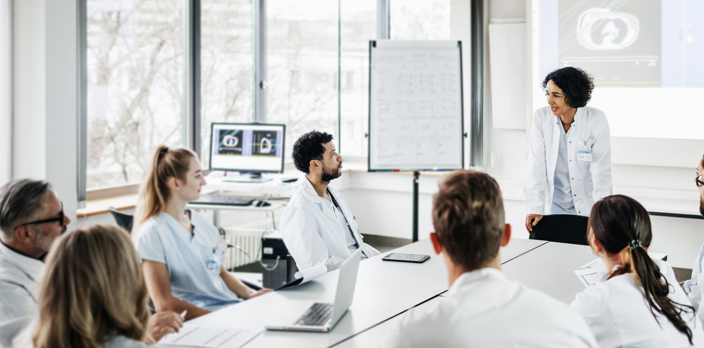 Hospital leaders sit around conference table in a meeting.