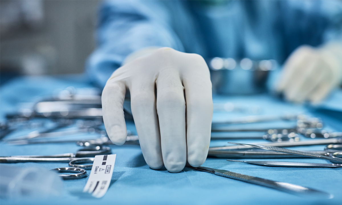 Gloved hands of physician organizing tools in operating room