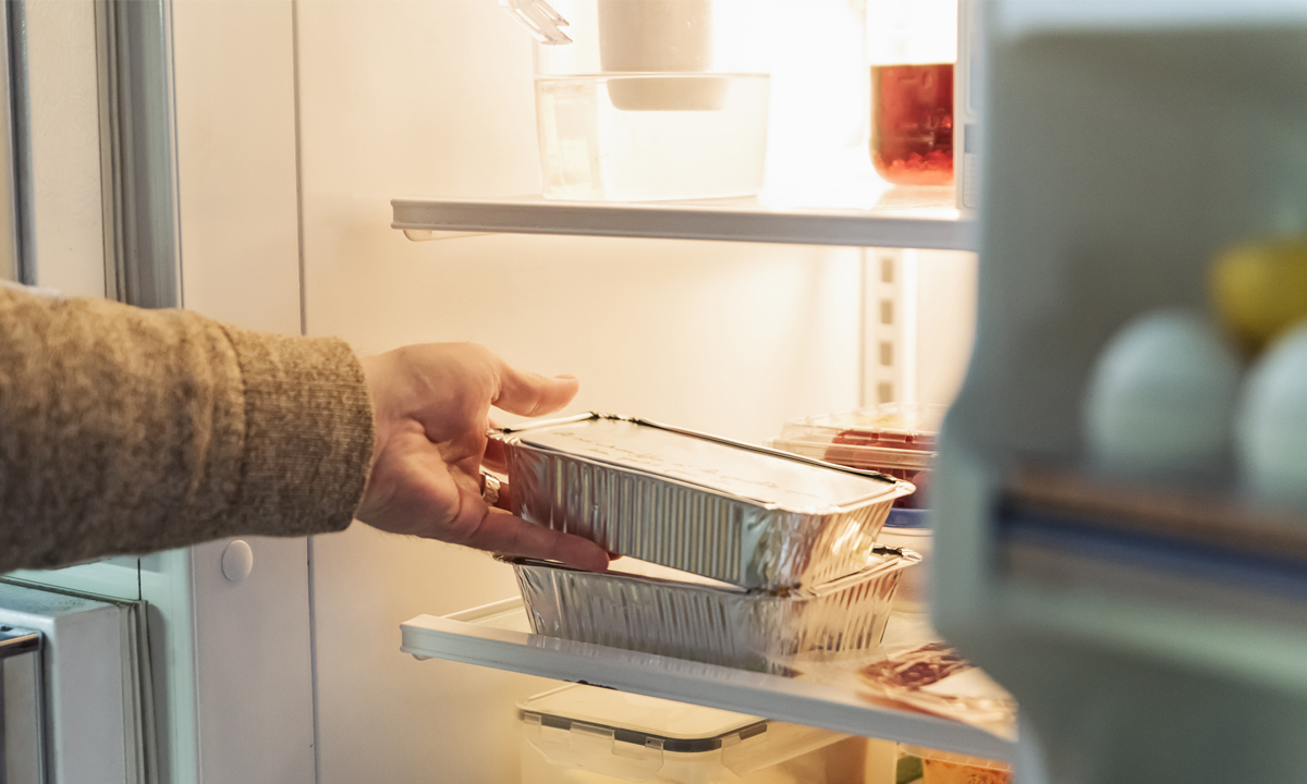 Hand taking takeout meal out of refrigerator