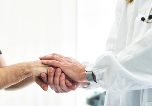 A doctor holding a patient's hand.