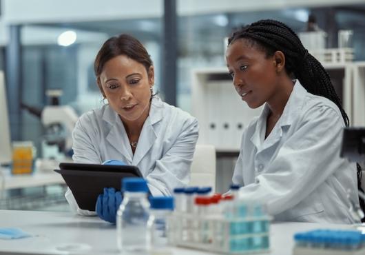 Two female health care workers talk in a lab.