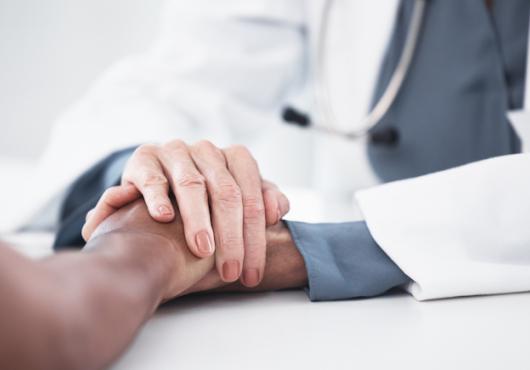 A physician holding the hand of a patient.