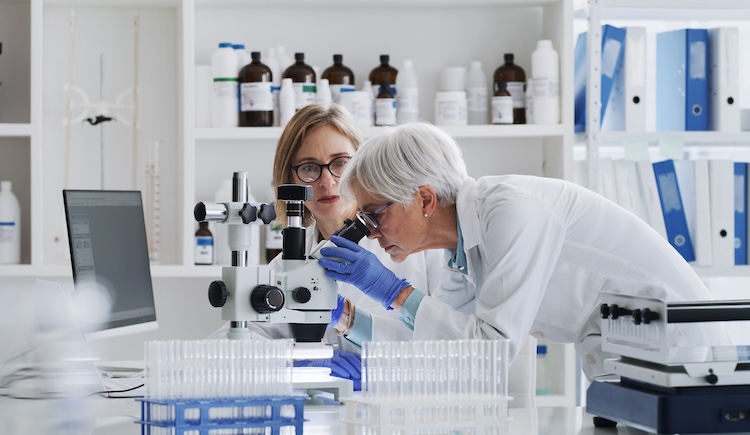 Two female health care workers talk in a lab.