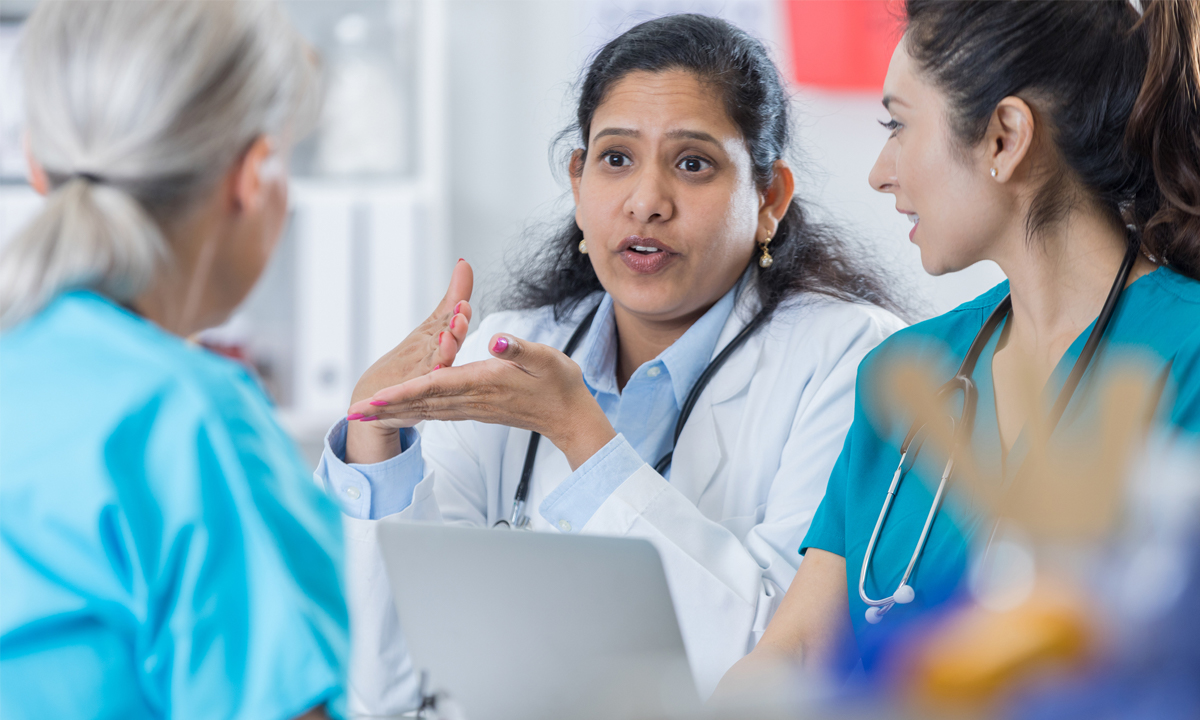 Three female physicians in a conversation.