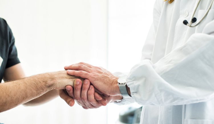 A doctor holding a patient's hand.