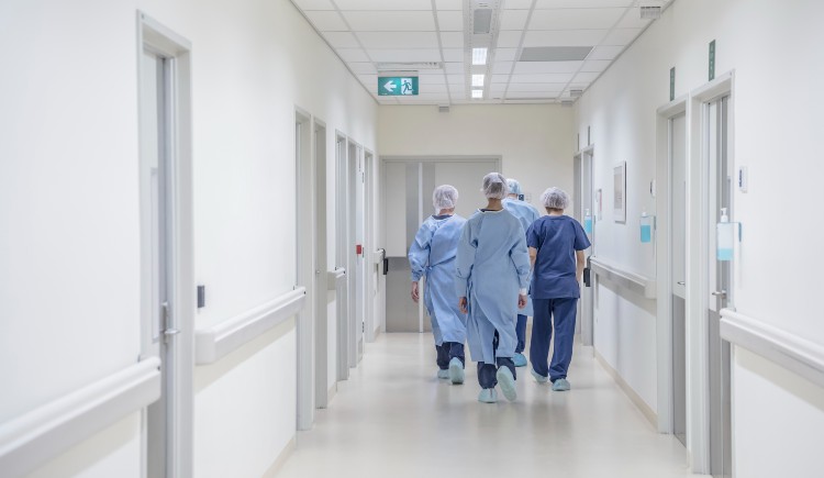 Medical professionals in sterile gowns walking down a hospital corridor.