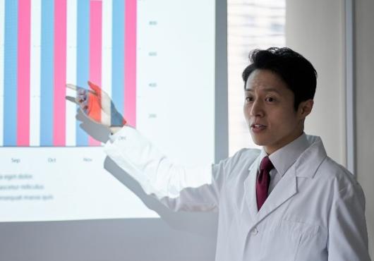 A doctor points to a powerpoint projected on a wall.