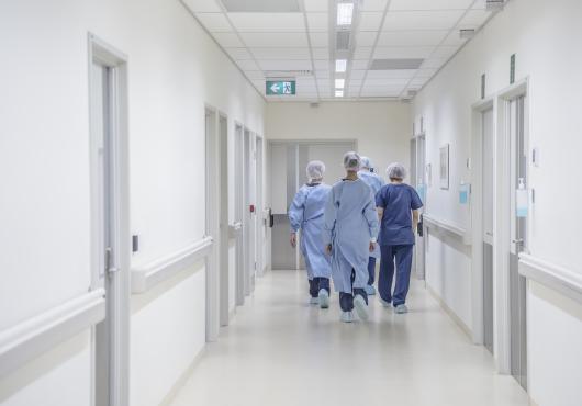 Doctors in sterile gowns walking down a hallway.